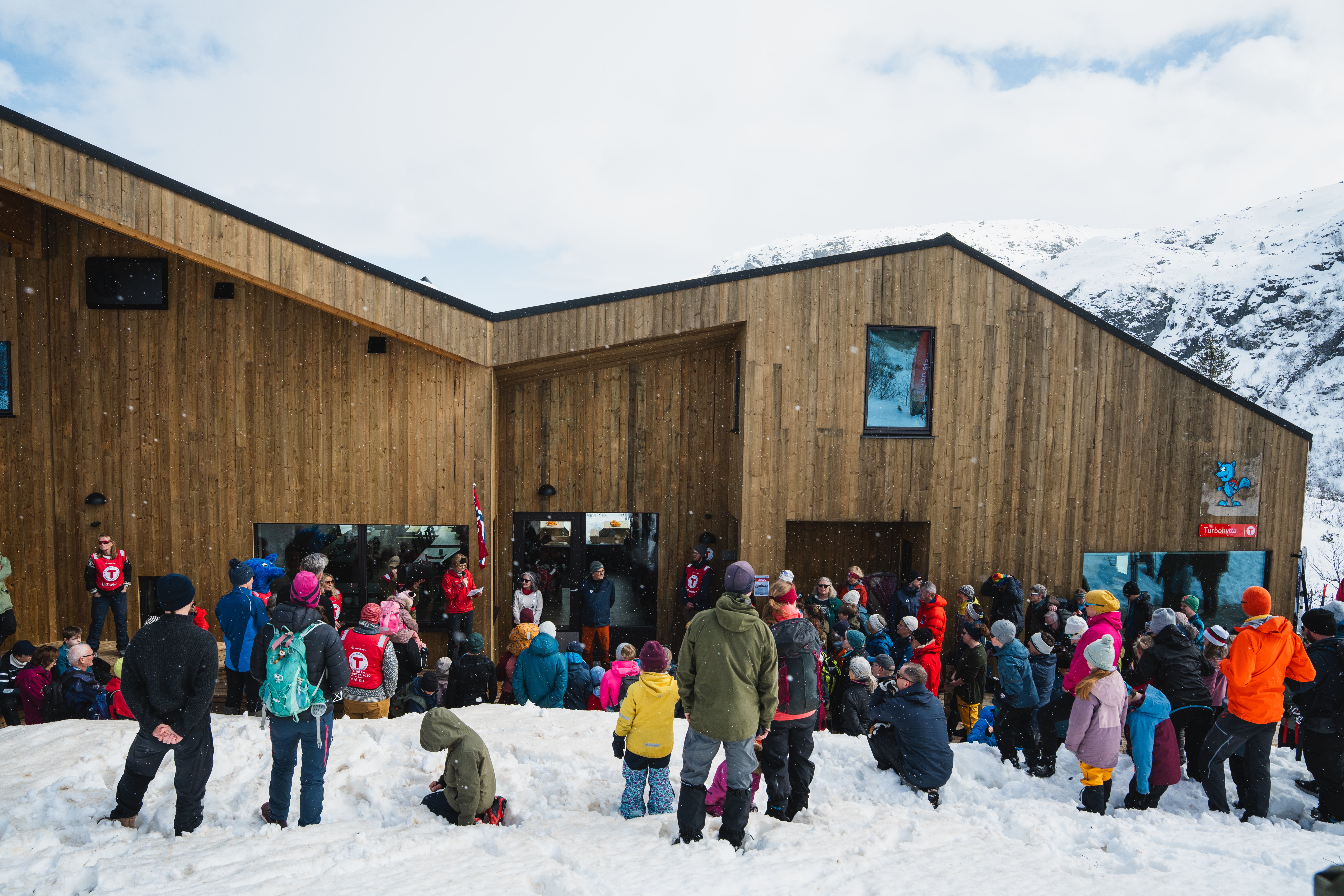 Mange folk samlet foran en ny og moderne hytte.