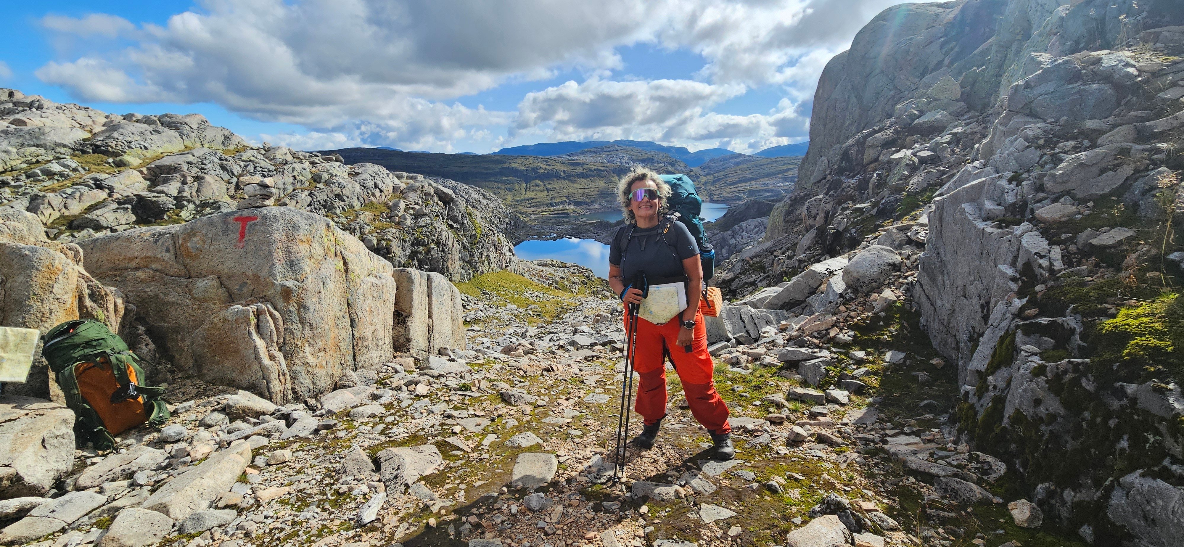 Kvinne i regnt&oslash;y i fjellterreng.