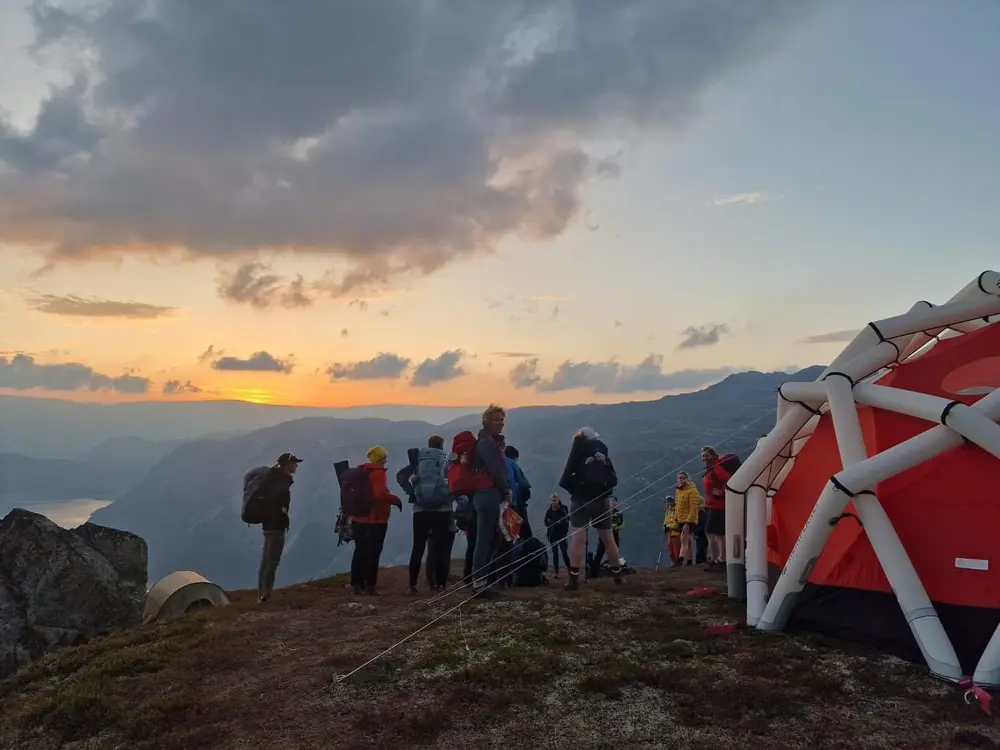 En gruppe på tur om kvelden foran et telt.