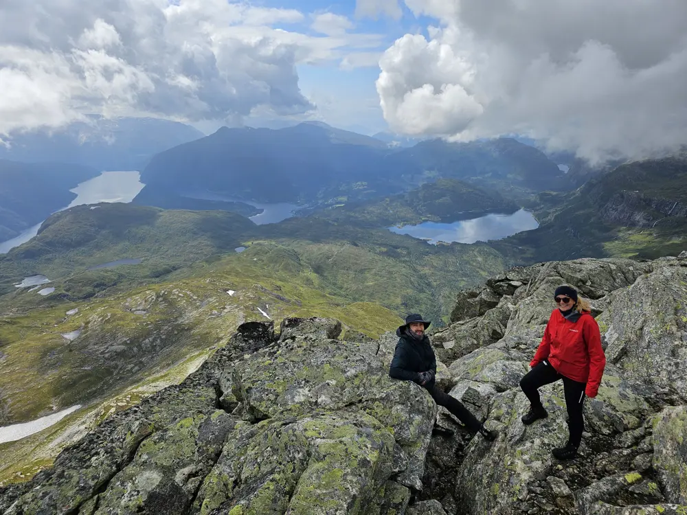 Kvite skyer, grøne fjellsider med fjord og vatn