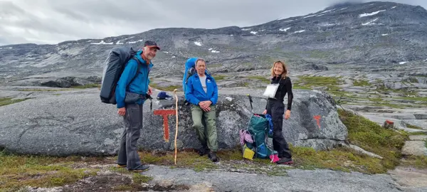 To menn og en dame har femminutt på tur i fjellområde