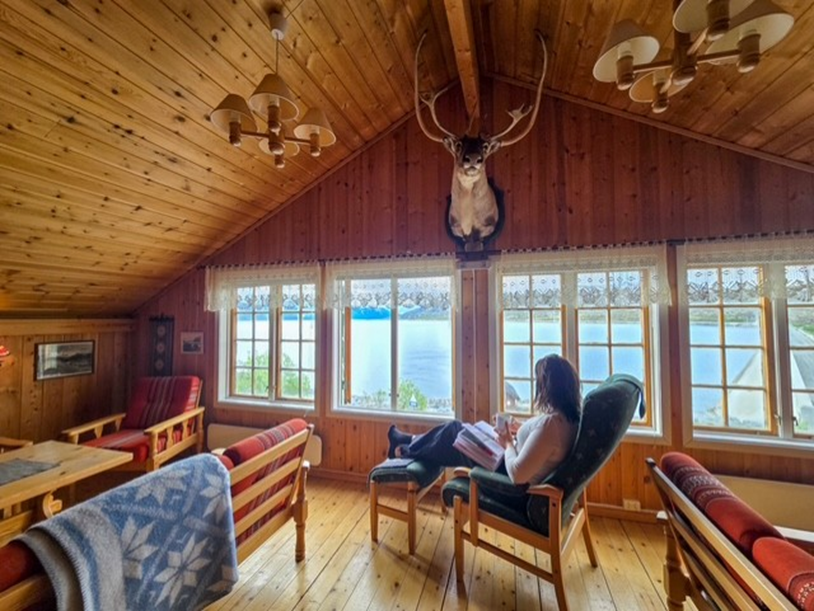 Gjest som drikker kaffe og nyter utsikt i stua fra andre etasje