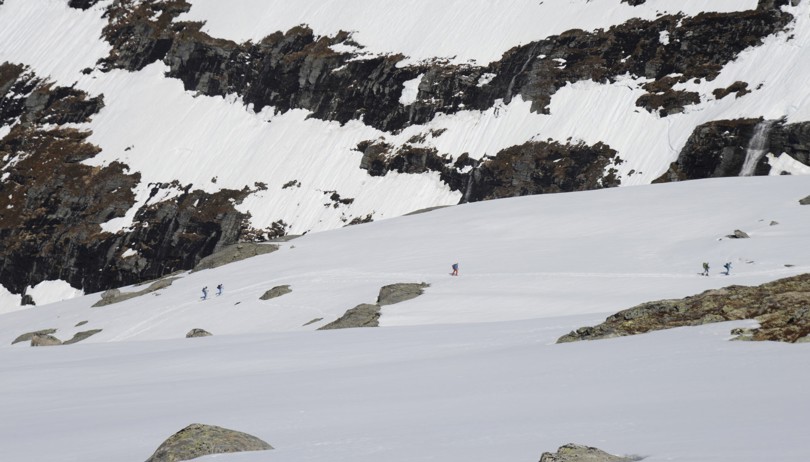 Fem personer går på ski opp ei fjellside.