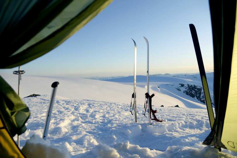Et par ski stikker opp fra snøen utenfor åpningen til et telt.