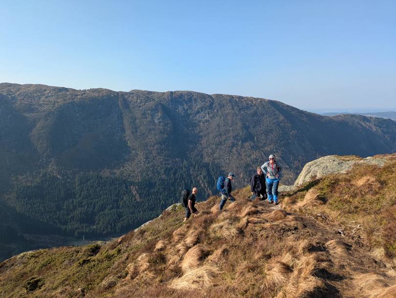 Gruppe mennesker på fjelltopp med utsikt.