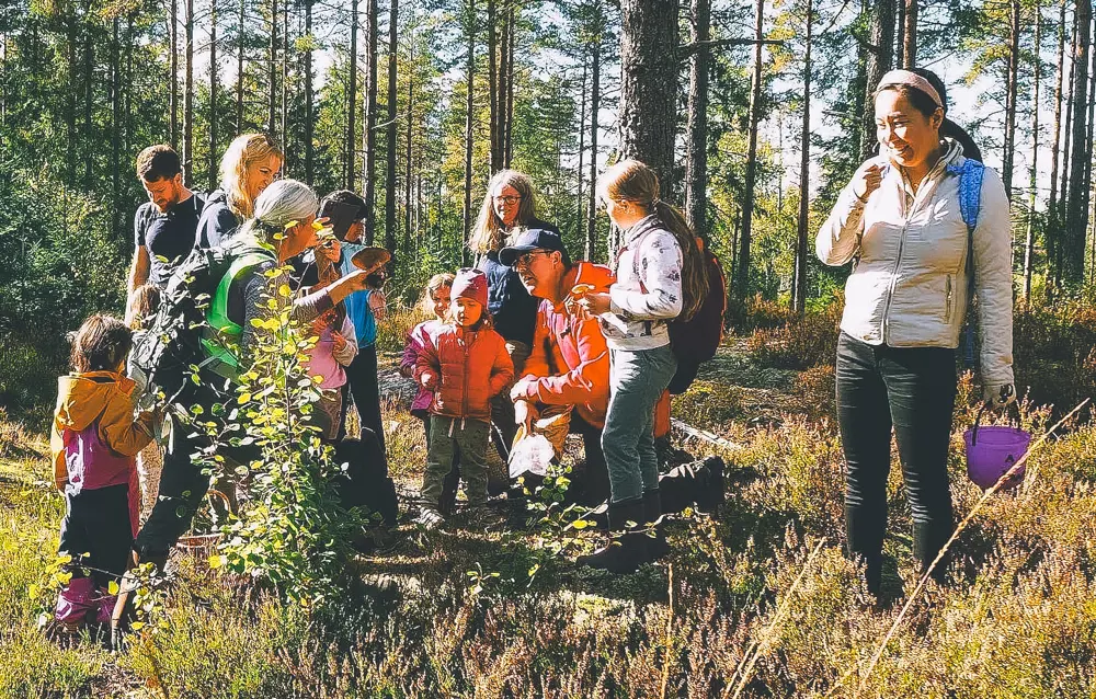 Barn og voksne på tur i skogen.