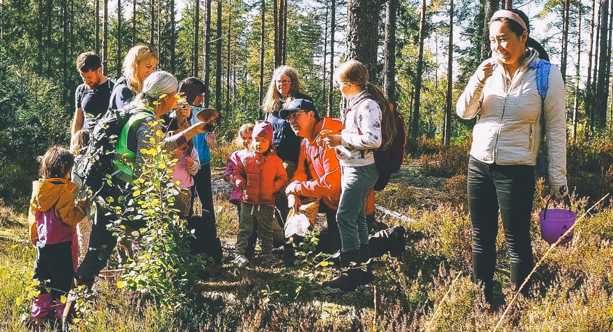 Barn og voksne på tur i skogen.