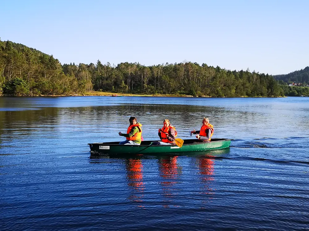 Tre personer sitter i en kano og padler et vann. Foto.