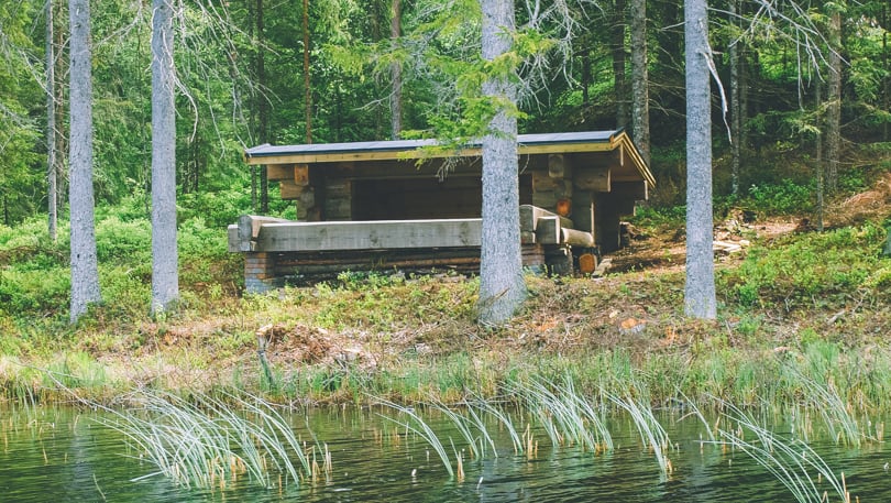 Gapahuk med vann i foran og skogen bak.