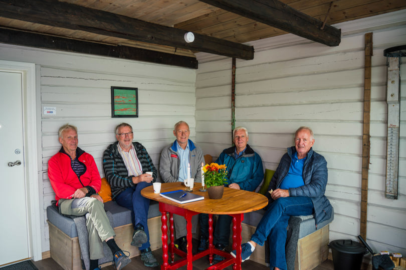 Fem menn i en sofakrok på en hytte.