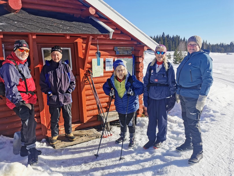 Blide personer på ski i sol.
