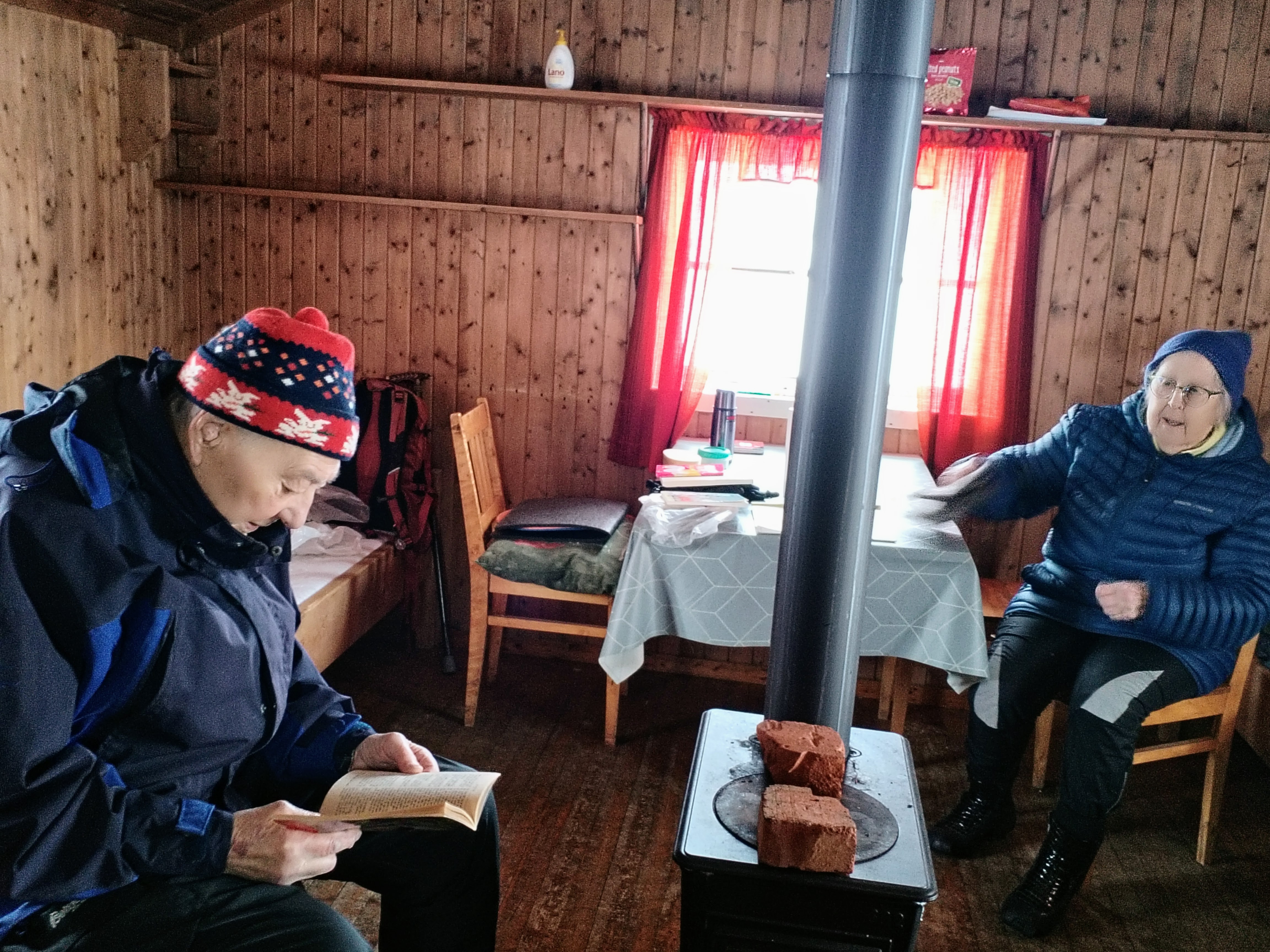 Mann og dame sitter ved vedovn.