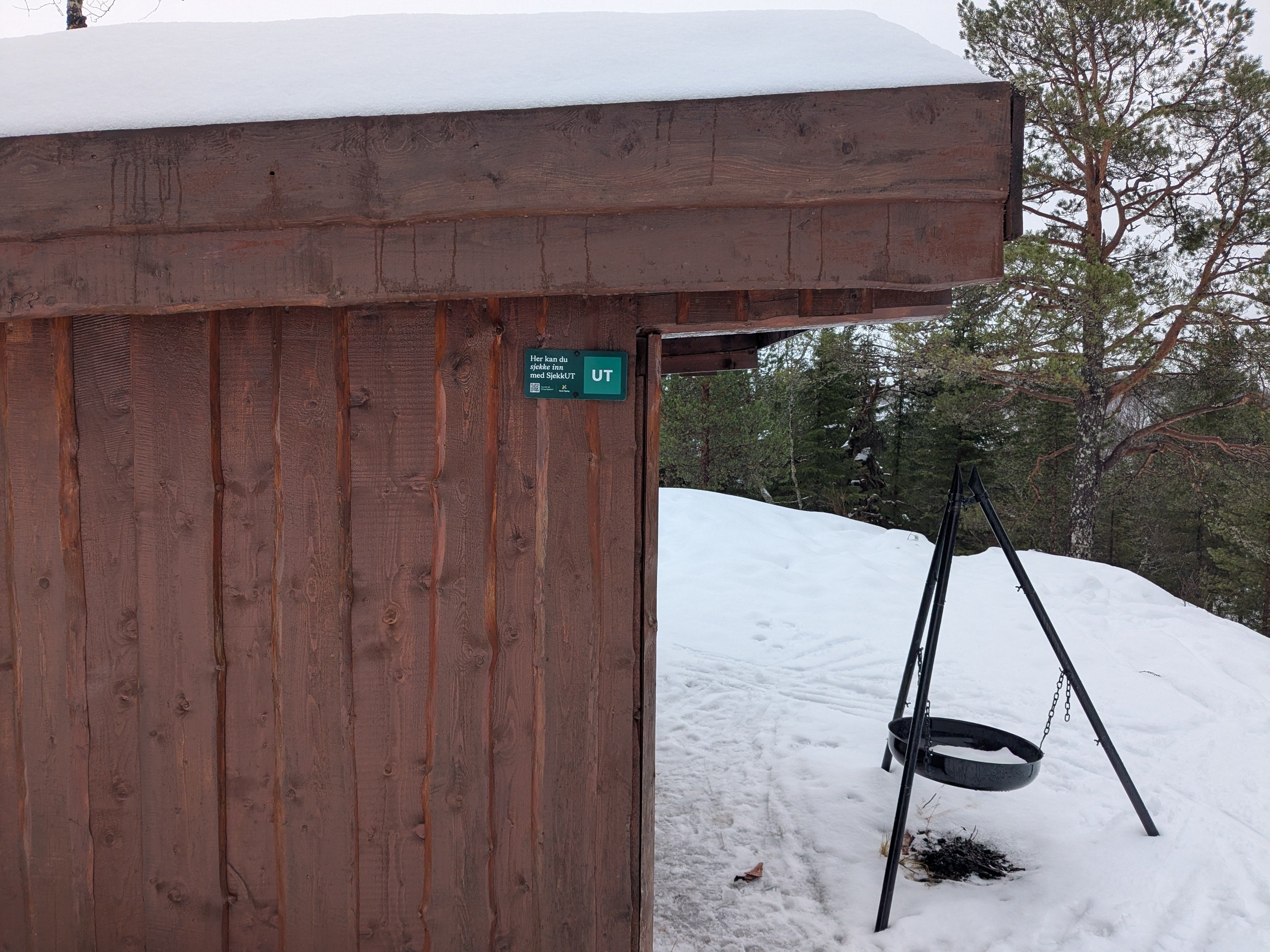 Gapahuk med skilt p&aring; og b&aring;lpannestativ foran