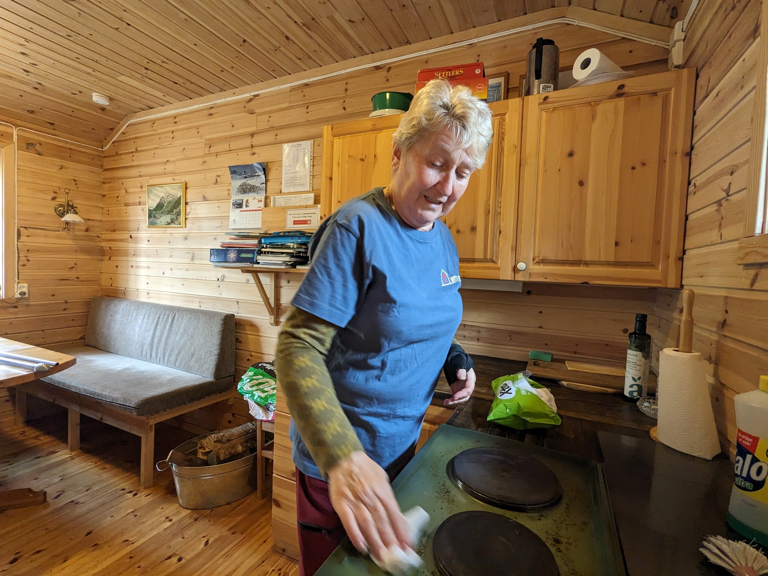 Dame rengjør kokeplater i ei lita hytte.