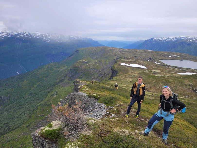 Kvinne og mann i fjellterreng med flott utsikt bak.