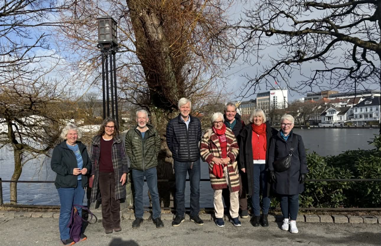 Bildet av en gruppe personer som st&aring;r ved et vann.