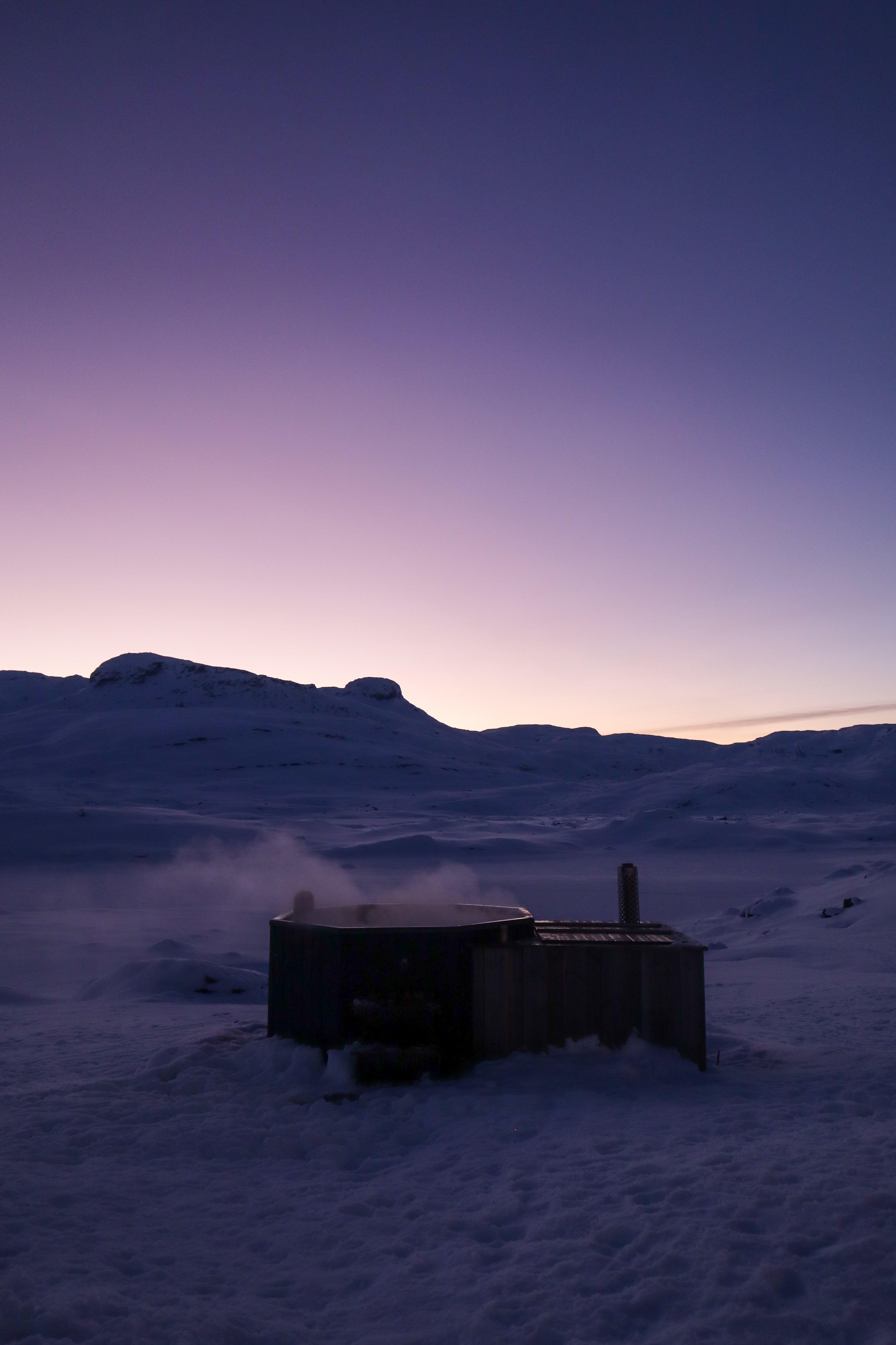 En person i en stamp, fjell og skumring i bakgrunnen