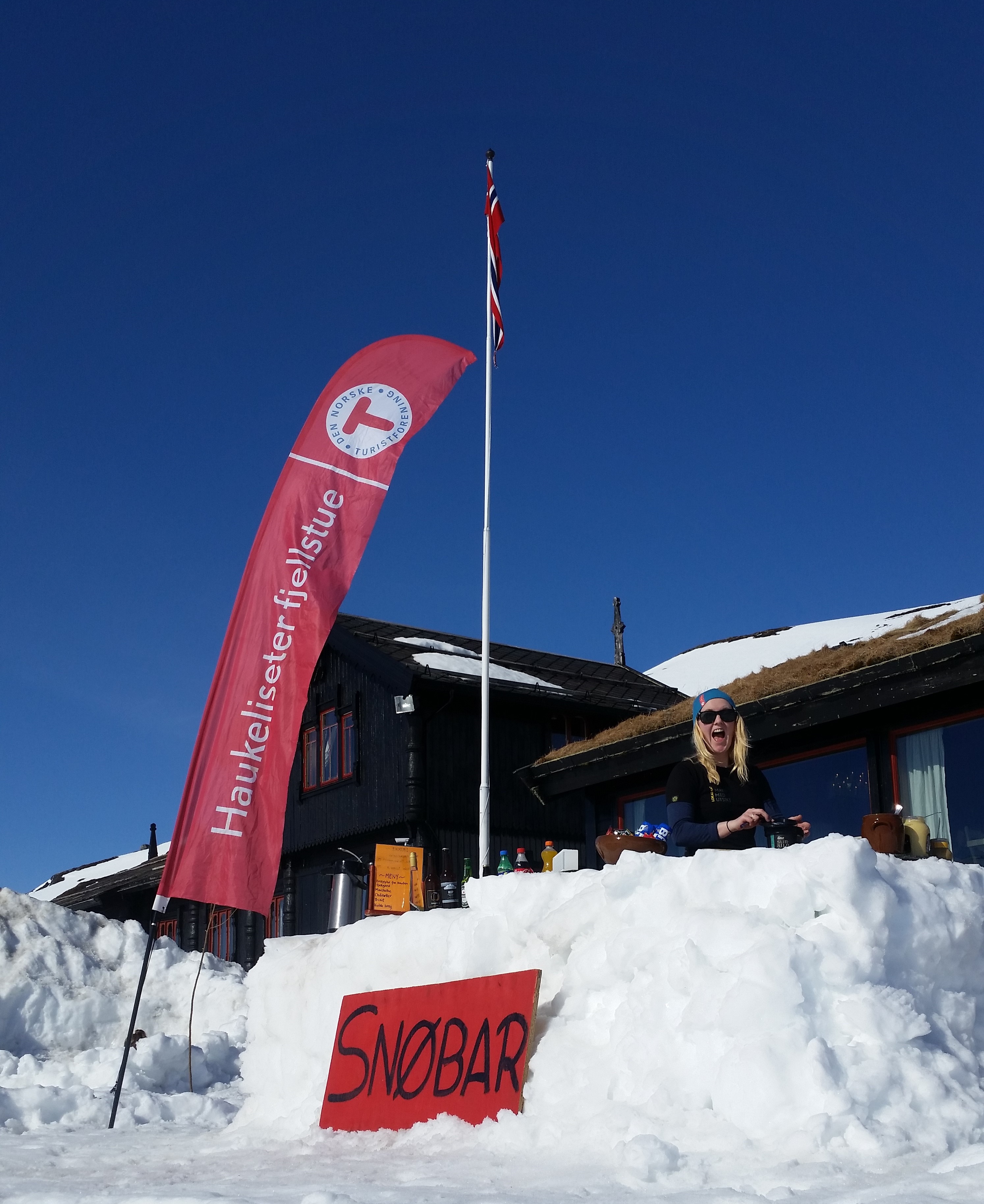 En glad dame selger forfriskninger i en bar laget av sn&oslash;. bl&aring; himmel