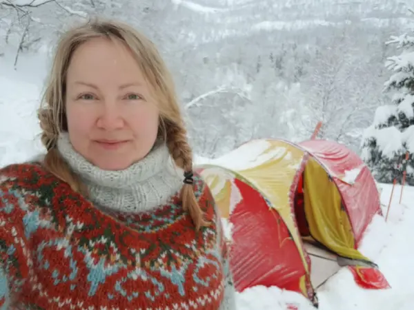Jente som står foran vintertelt. Snø på bildet.