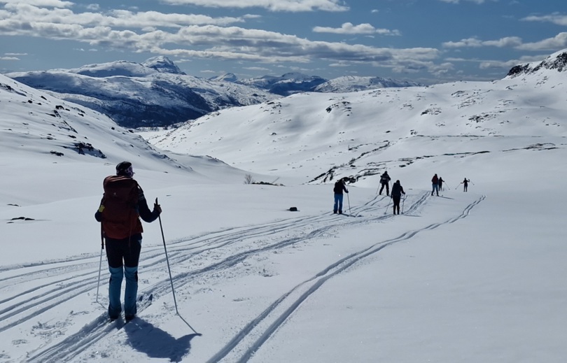 Skiløperne renner ned fra fjellet med utsikt over fjell