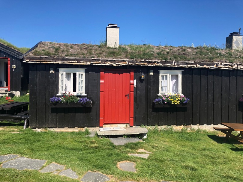 Svartmalt hytte med en rød dør