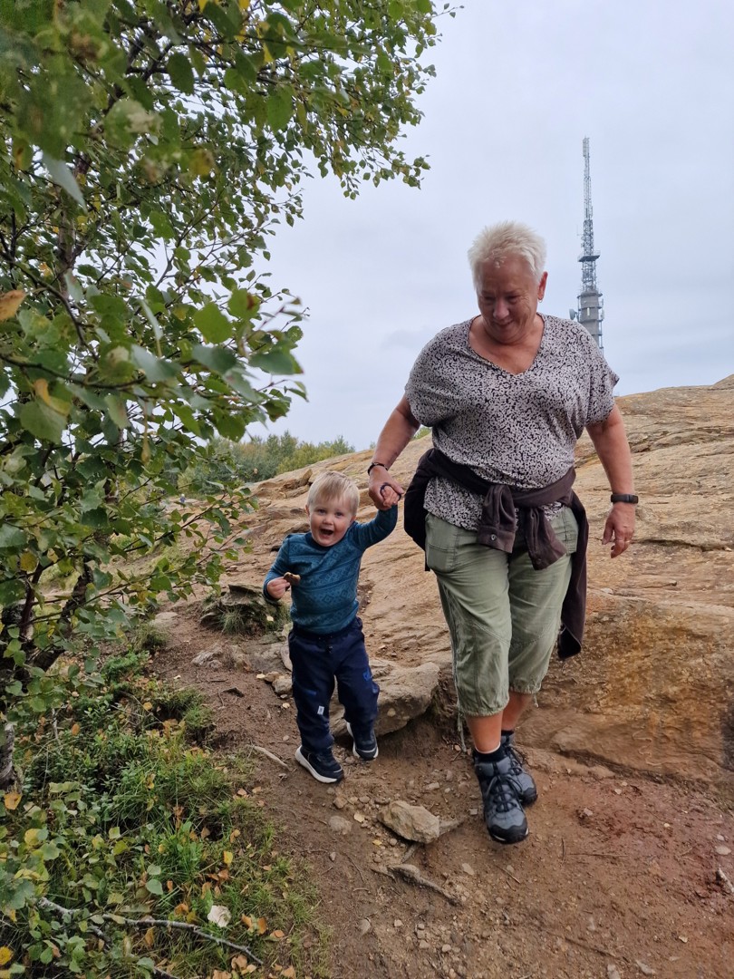 En eldre dame leier en liten gutt som hopper av glede