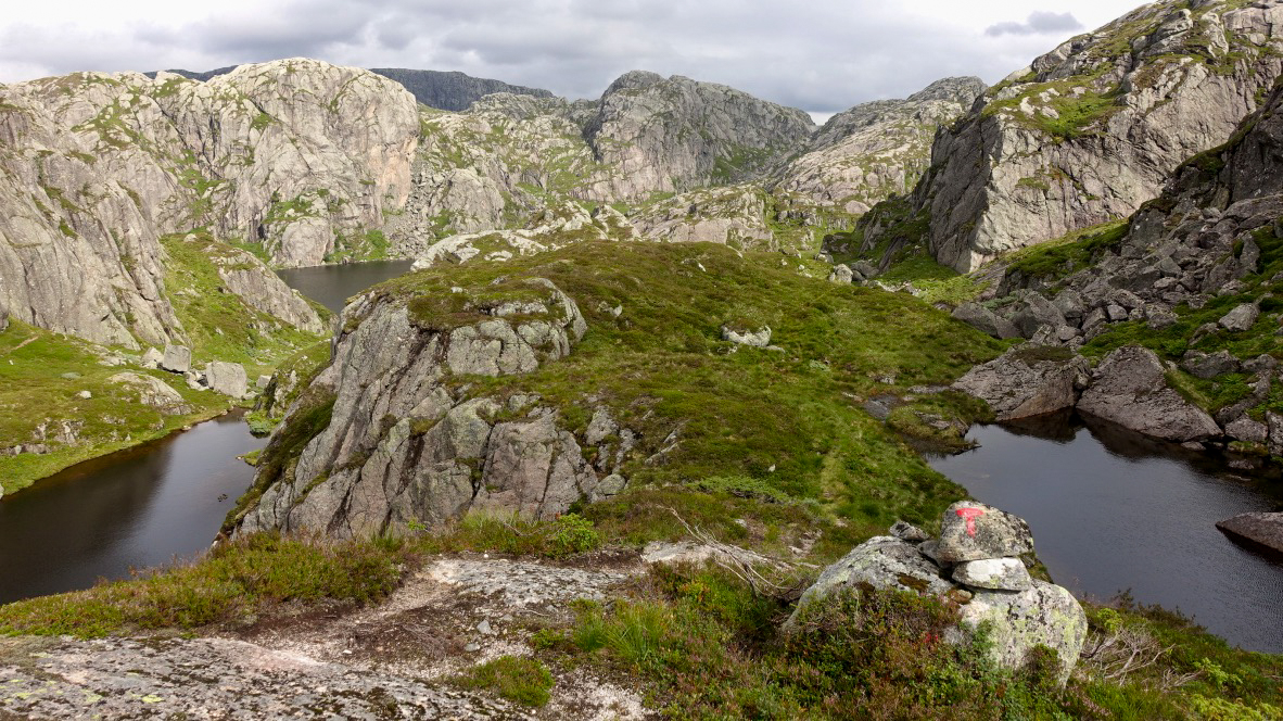 Bilde av en stein med en r&oslash;d T i et storsl&aring;tt fjell-landskap.