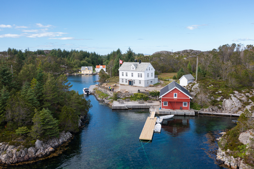 Hvit hytte med naust ved kysten