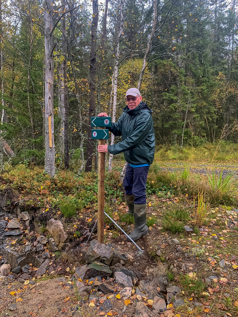 En mann som står og holder i en turskiltstolpe.