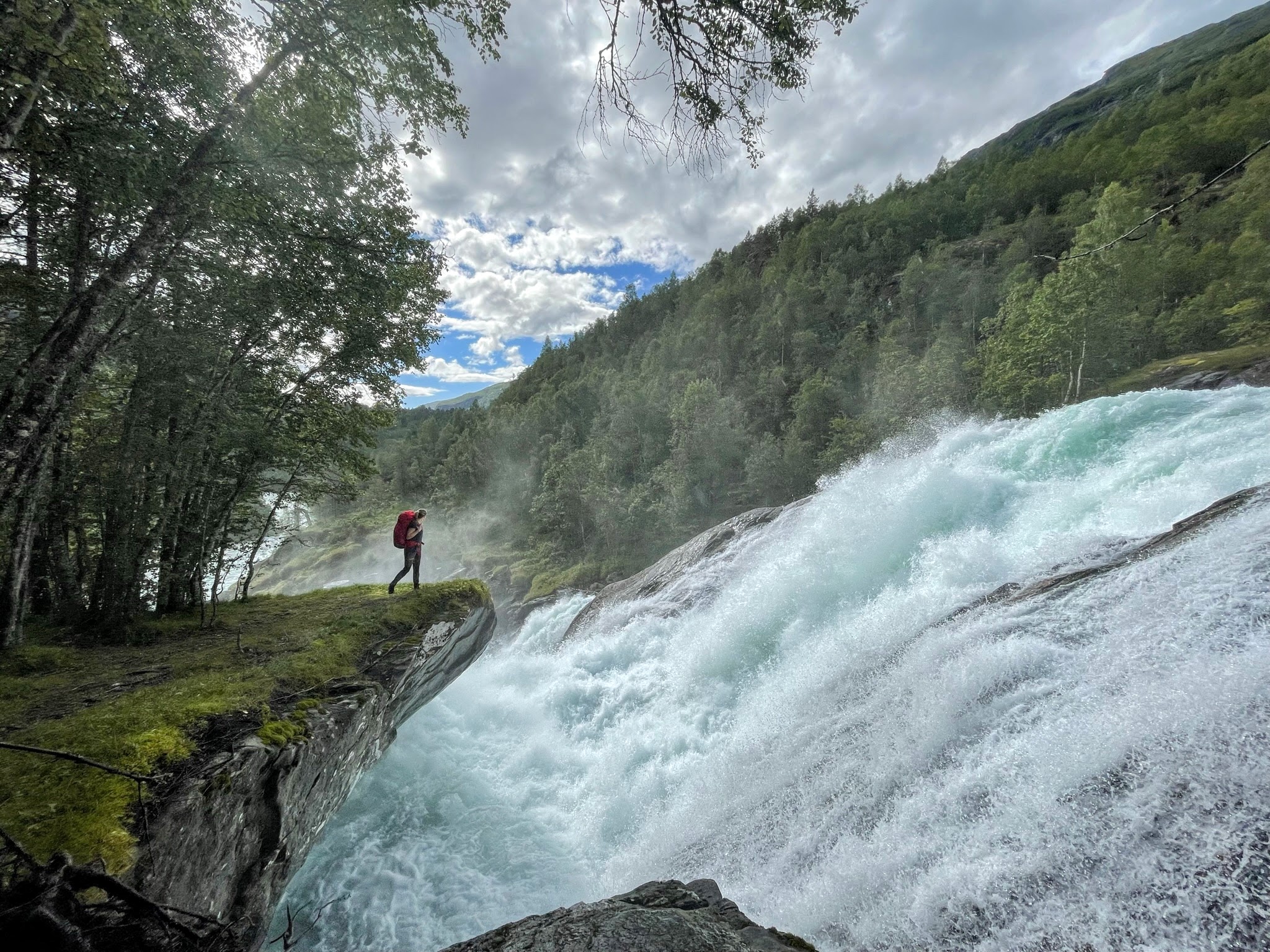 kvinne p&aring; utstikker over vakkert fossefall