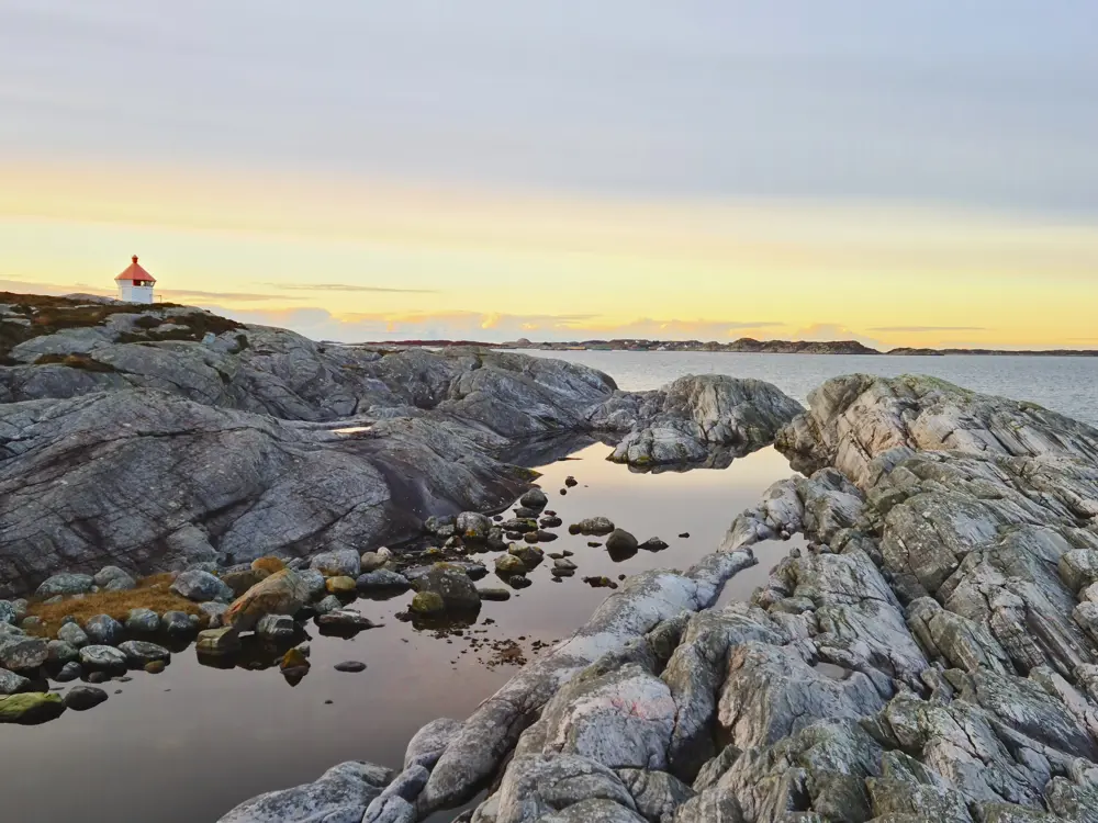 Svaberg og fyrlykt i solnedgang. Et lite vann. Foto 