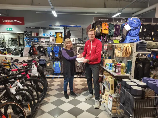 To personer viser fram samarbeidsavtale i sportsbutikk