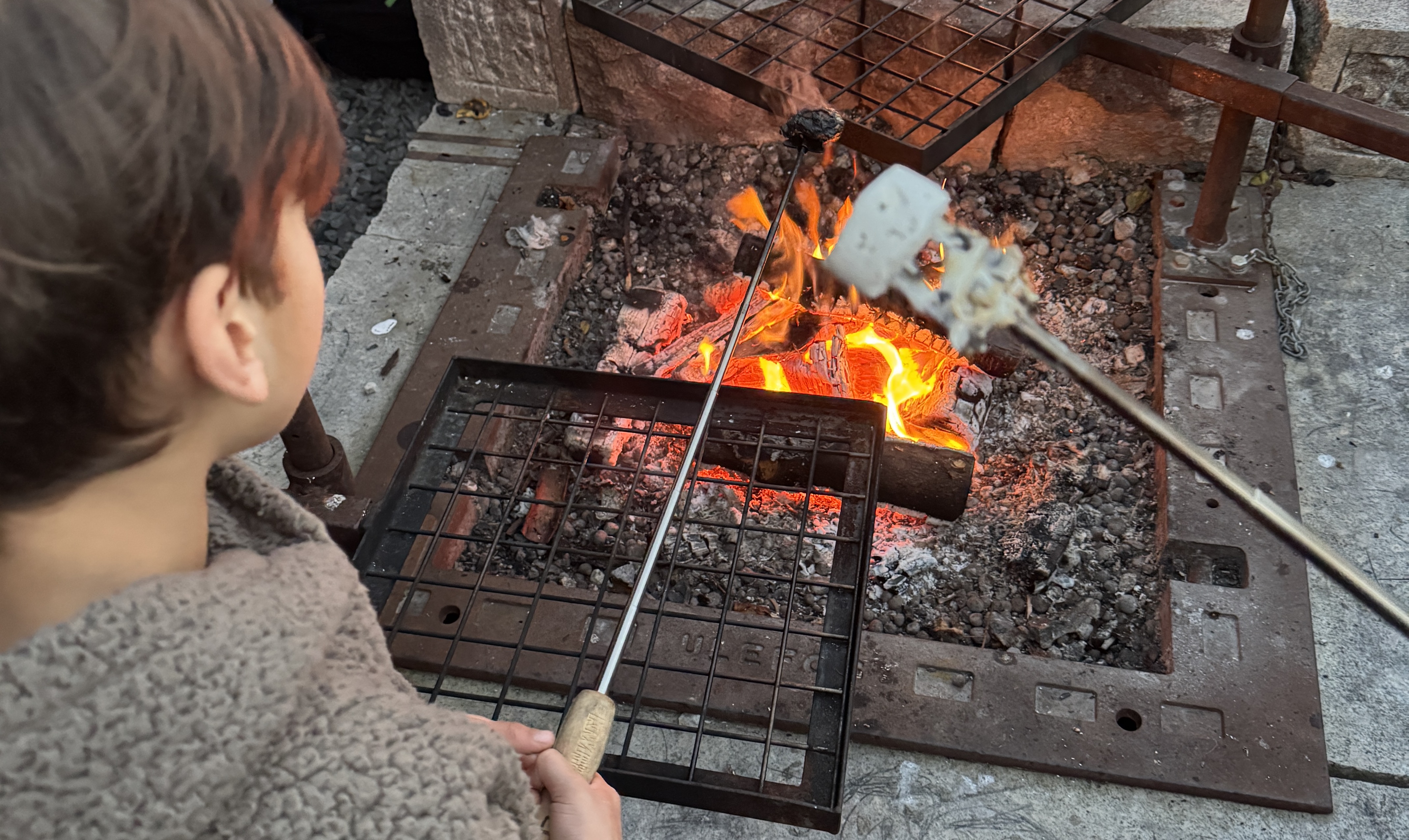 En gutt som griller marshmallows på en utegrill.