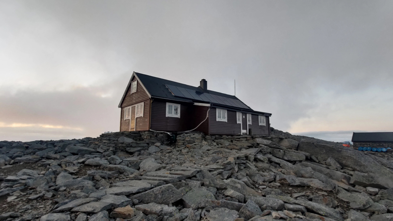 En brunmalt hytte med solceller på taket