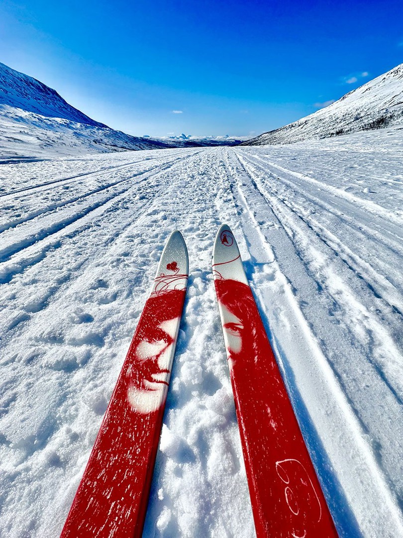 Bilde av et par skitupper og en oppkjørt løype. Snø og hvite fjell på begge sider av løypa.