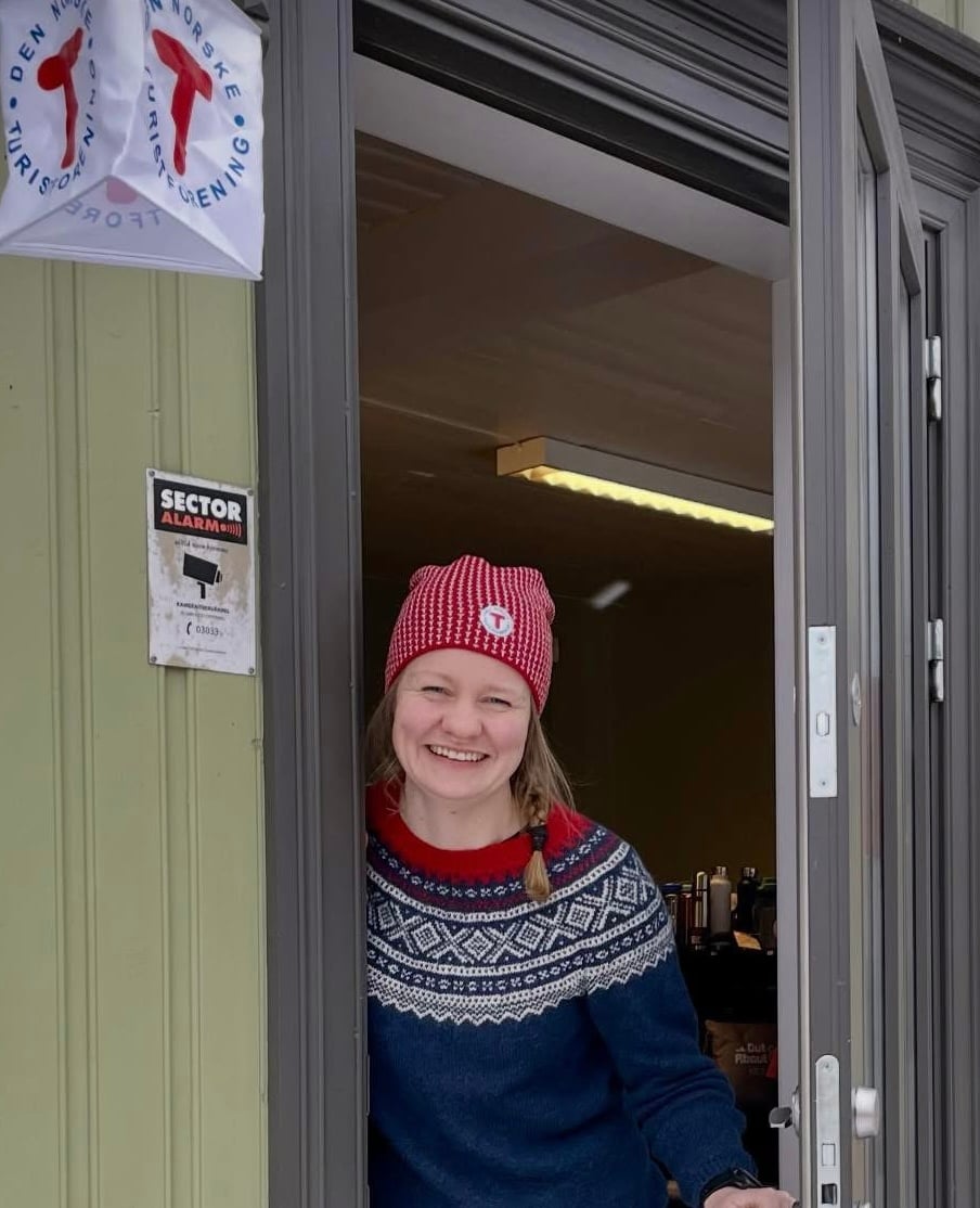 kvinne som står i en døråpning og smiler