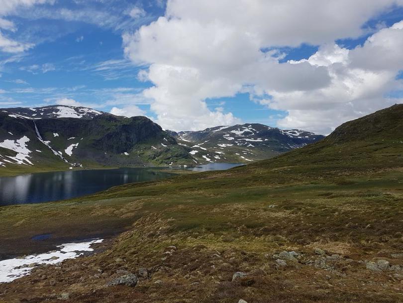 Vakker utsikt med fjell, fjellvann og snødekte tuer. 