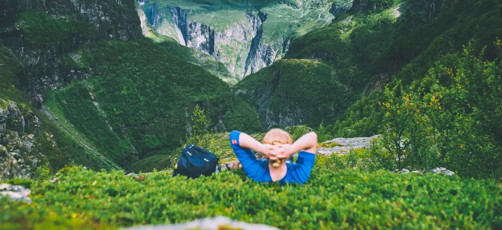 Mann ligger i lyngen og ser utover dal.