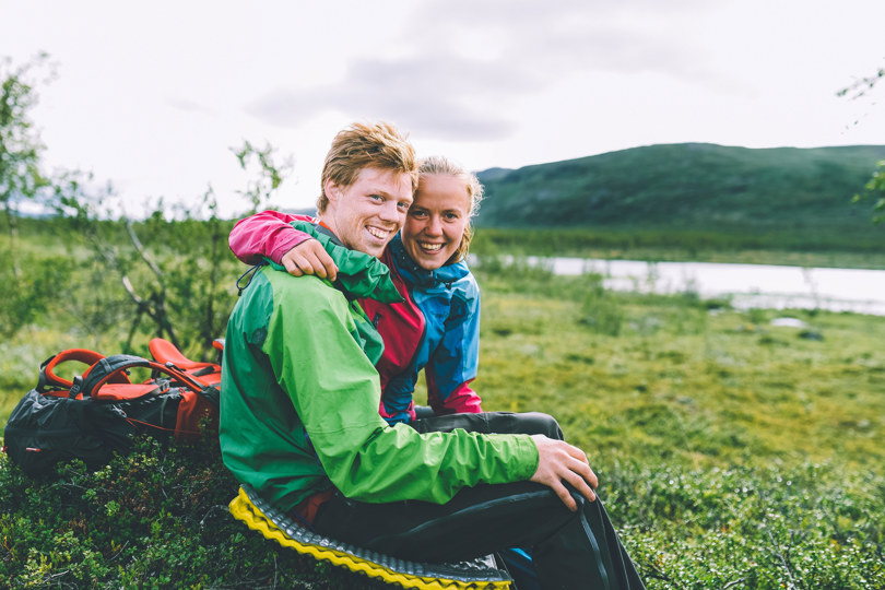 Ungt par som holder rundt hverandre i vakker natur.