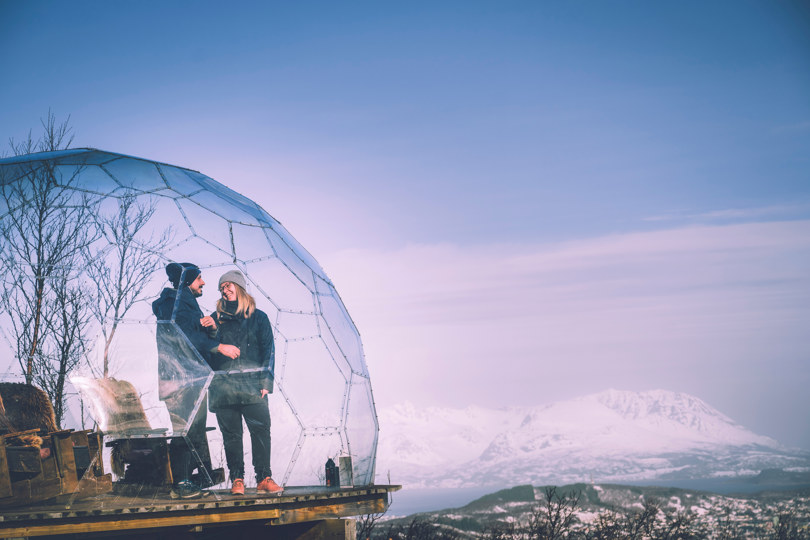 Et par som stor står i en gjennomsiktig kuppel på en topp i Harstad. 