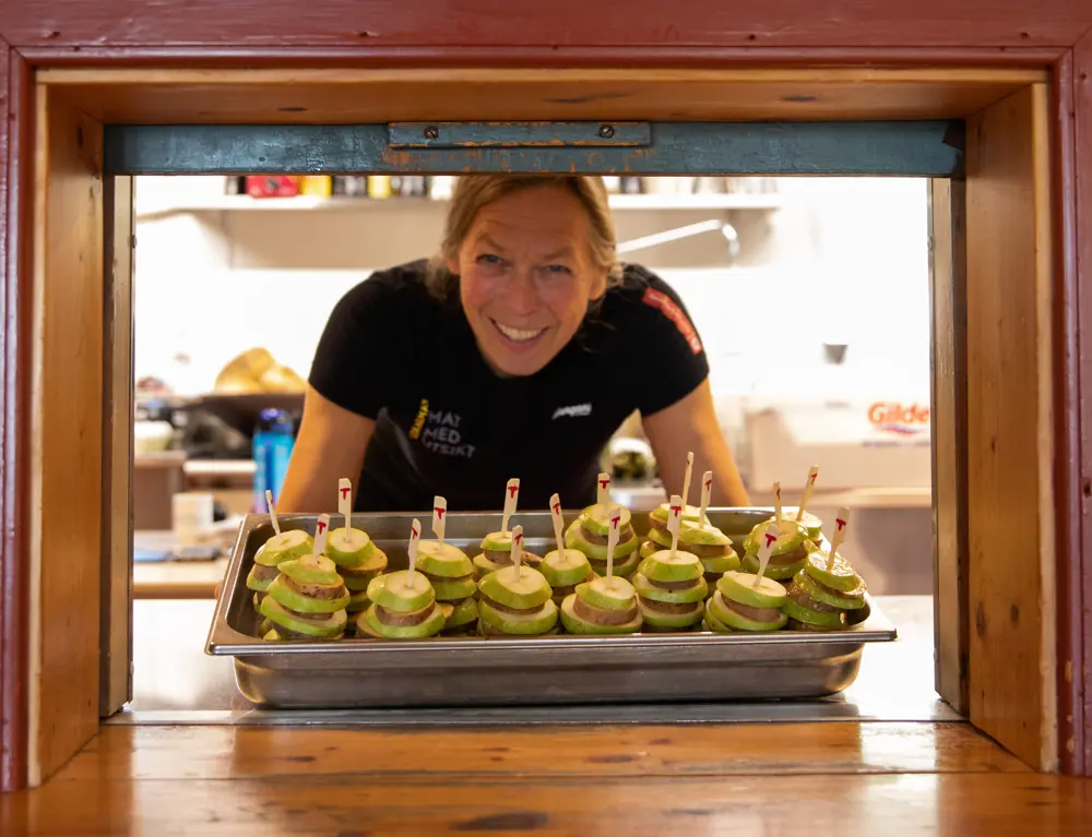 En smilende ansatt frister med danderte eple- og pærepinner.  