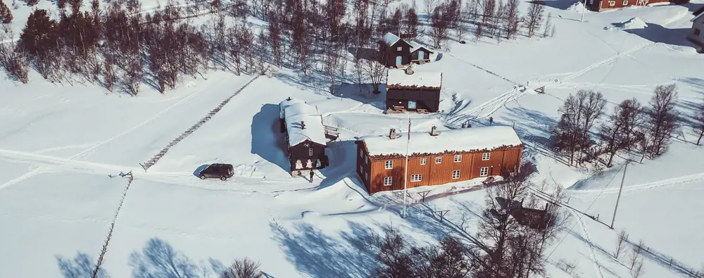 Dronebilde av Svukuriset, både tak og gårdsplass dekt i snø. 