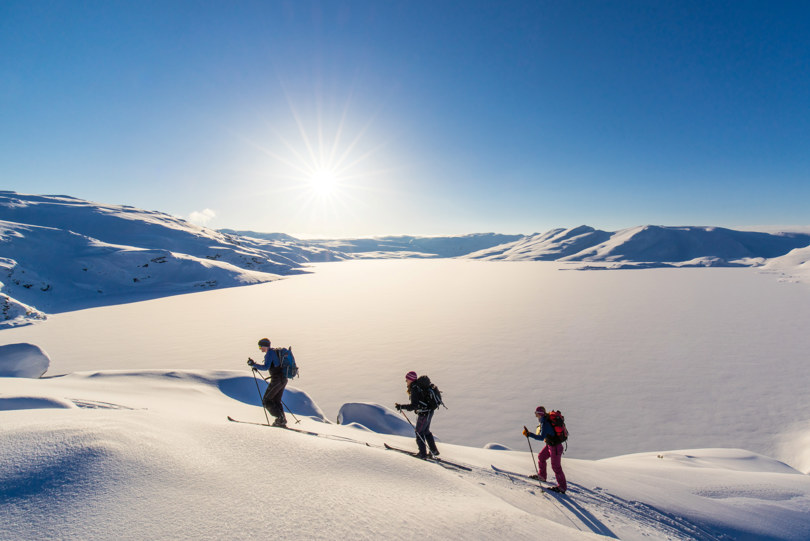 Tre skiløpere i vinterfjellet. Foto