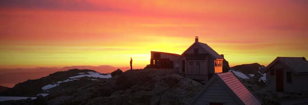 Person i siluett på en fjellknaus ved Fonnabu turisthytte.