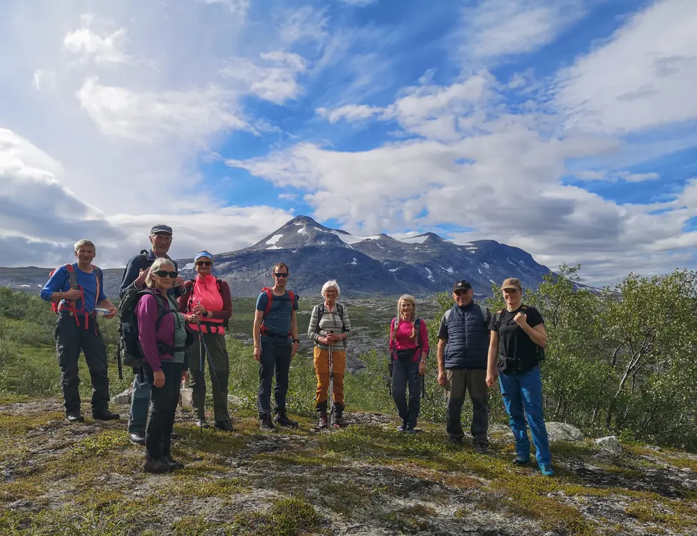 Turfølge som tar seg en pause på tur i Saltdal i nydelig sommervær. Majestetisk fjell i bakgrunnen.