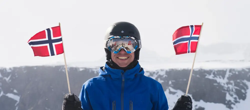 Flagging på Rasletind, en smilende fyr med skibriller og et norsk flagg i hver hånd.  