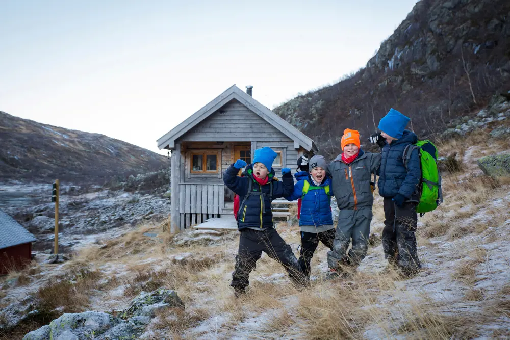 Fire barn står foran hytte i fjellet
