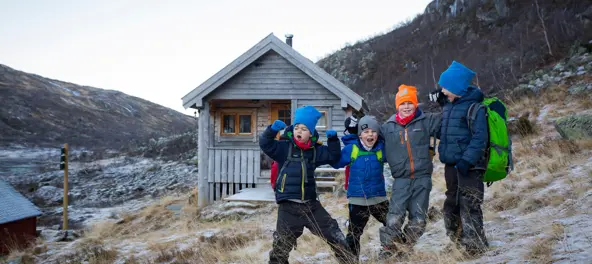 Fire barn tuller foran hytte i fjellet