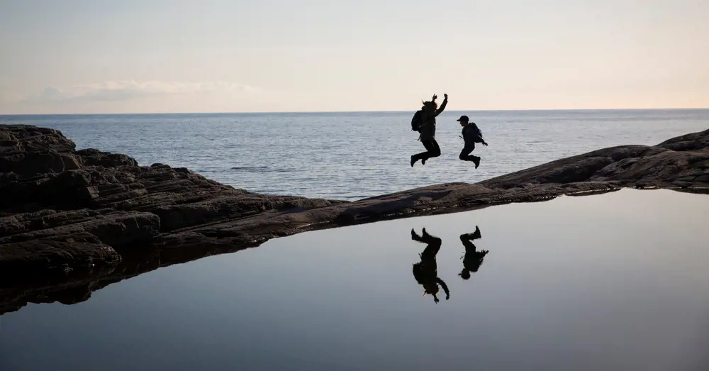 To personer hopper i solnedgang ute i havgapet. Foto 