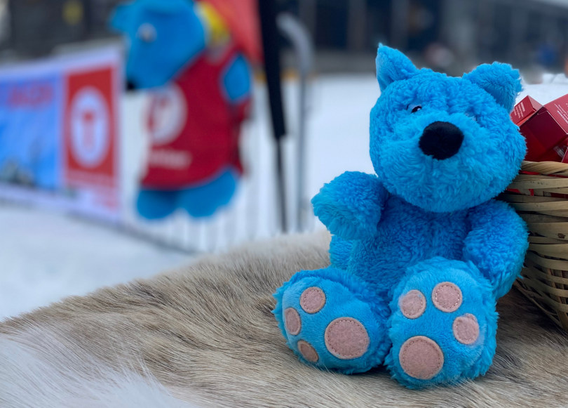 En blå bamse som er barnas turlag sin maskott i vinterlandskap